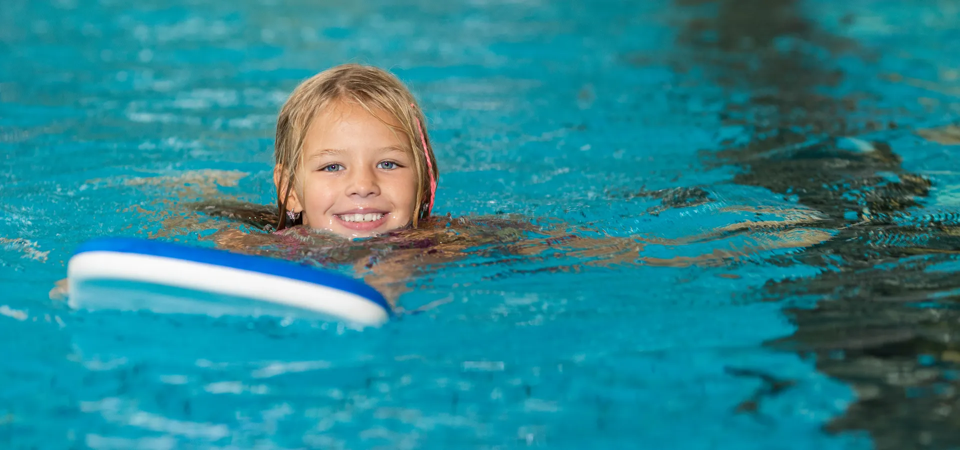 Kind schwimmt mit Schwimmbrett