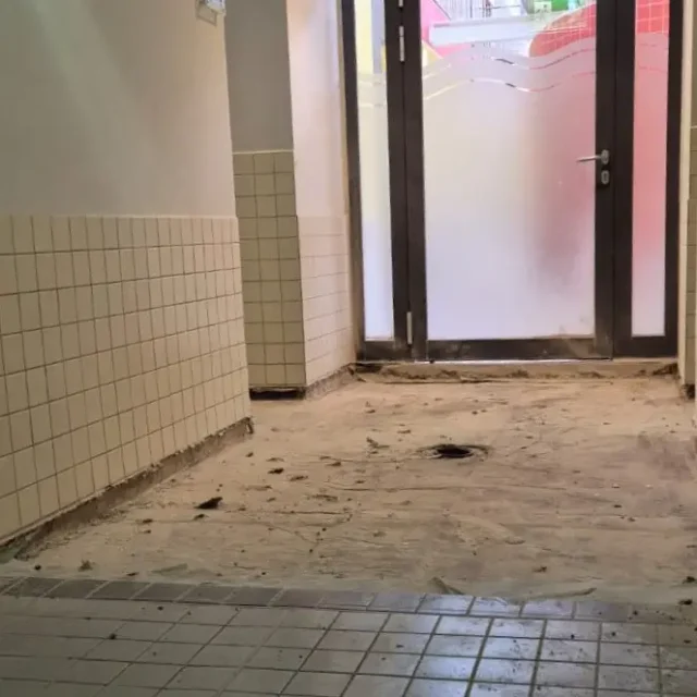 Gang zu den Sammelduschen. Die Bodenfliesen wurden entfernt.
