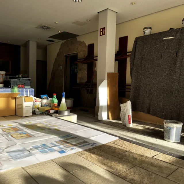 Eine technische Zeichnung ist im Vordergrund. Arbeitsmaterial steht im Hintergrund.